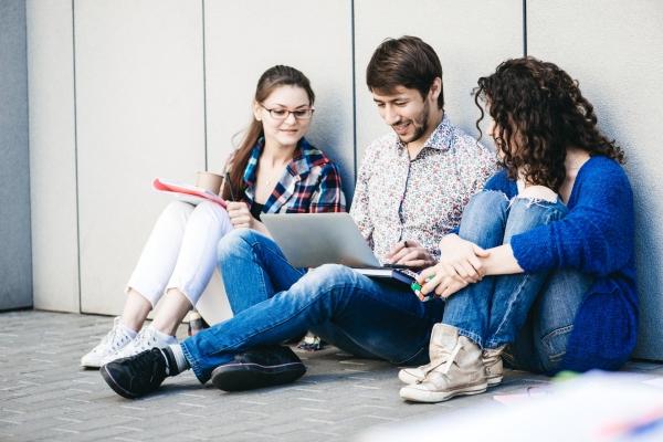 Young people are using different gadgets and smiling, sittin